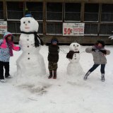 Emilia, Noah, and Juliette with their snowman and showgirl