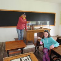 Miss Jeanie disciplines her pupil in Portsmouth Village's schoolhouse.