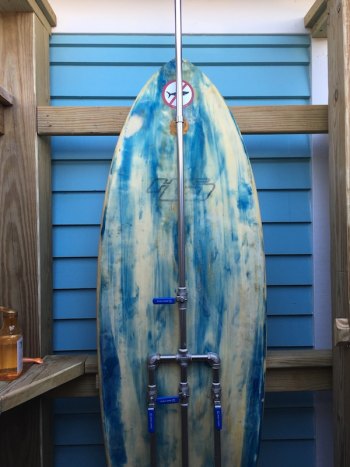 The outdoor shower features a repurposed surfboard.
