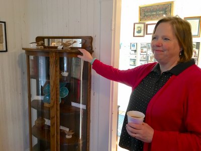 Administrative Assistant Mary Bryant shows a new piece to the museum, a china cabinet from the collection of Kenny Ballance.