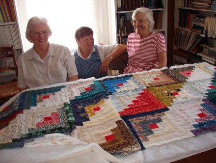 Ocracoke quilters pose with a quilt-in-progress at the OPS Museum in 2001. Left to right: Cricket Ware, Agnes Wren, and Lewis Thomas. Cricket passed away in 2004; Agnes now lives in Virginia.