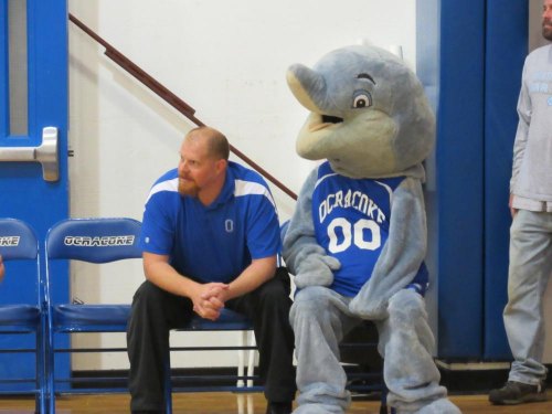 JV coach Denny Widener watches a game with Splash, the Dolphins' mascot.
